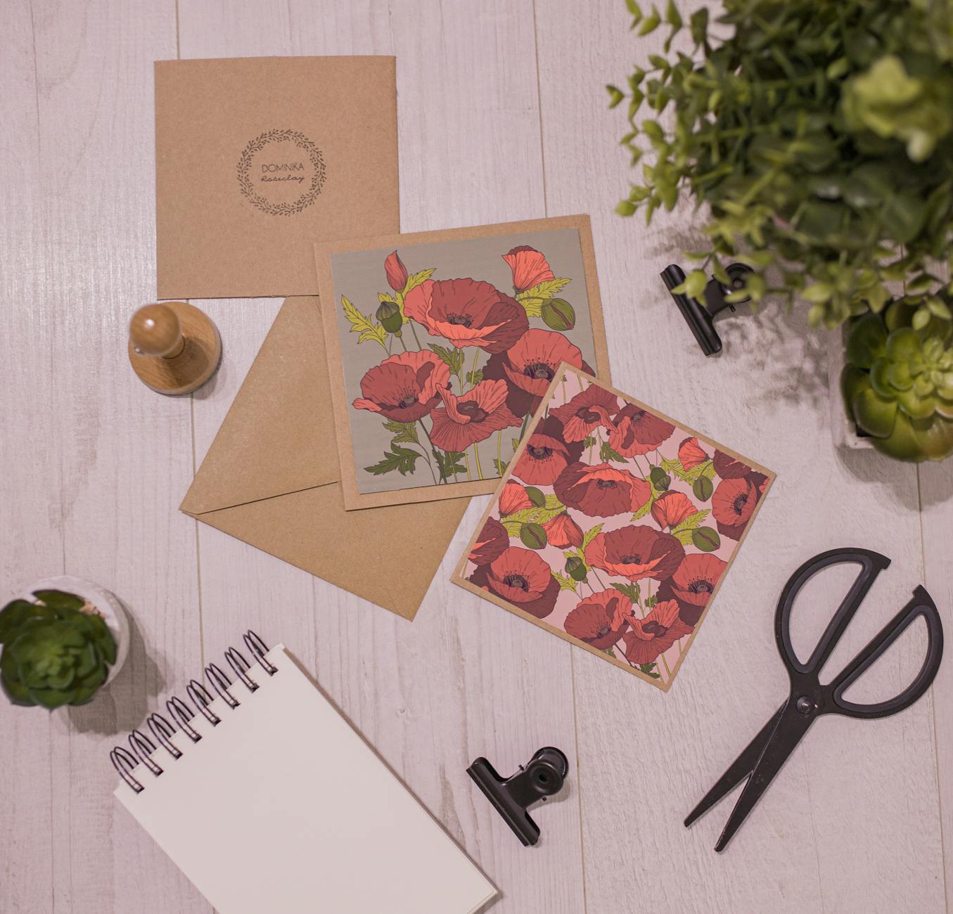 Layout of fresh succulents and creative handmade postcards with flowers pictures on white wooden table composed with scissors and notepad