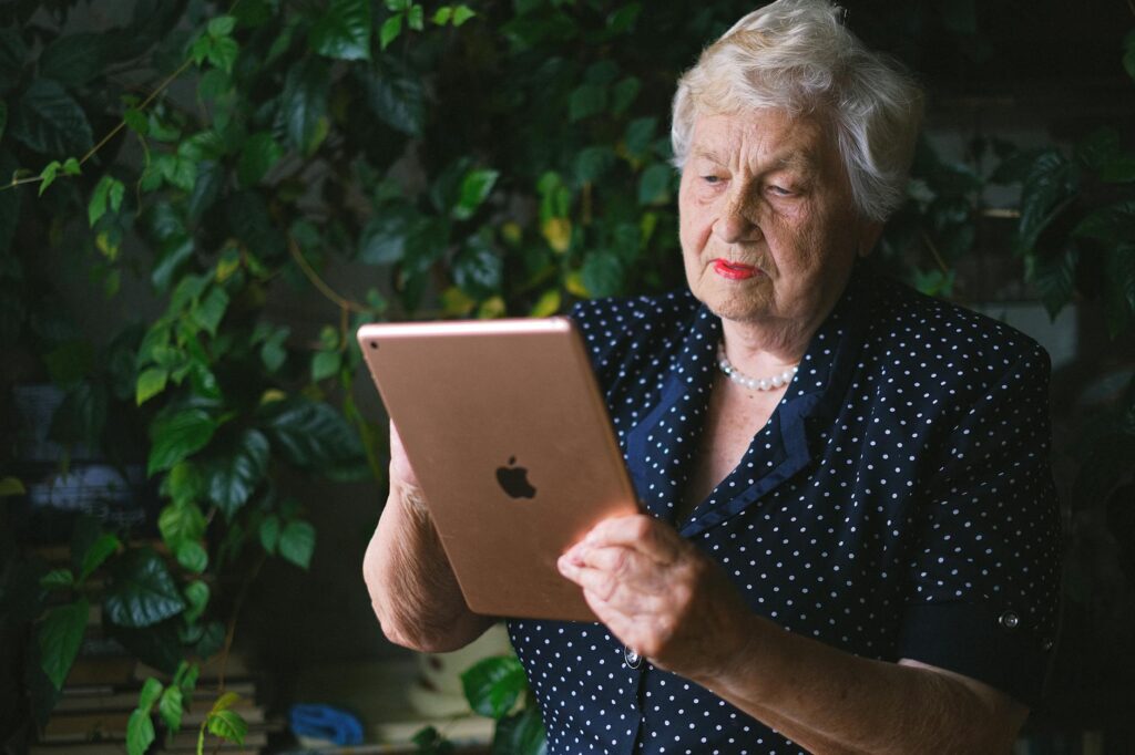 Senior woman touching screen of contemporary tablet